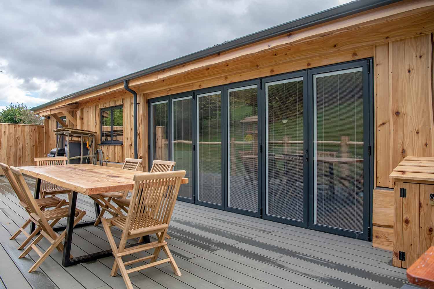 Blinds in Glass in Baldock: integral blinds in the bifold doors of a garden lodge, viewed from the decking