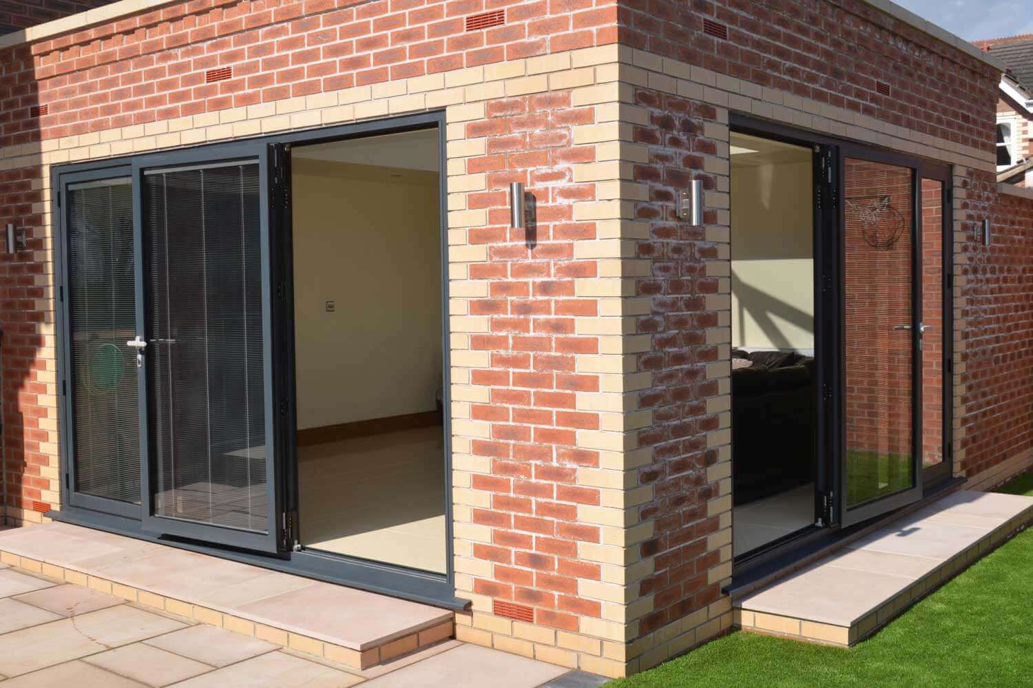 Blinds in Glass in Baldock: integral blinds in the corner bifold doors of a brick garden room